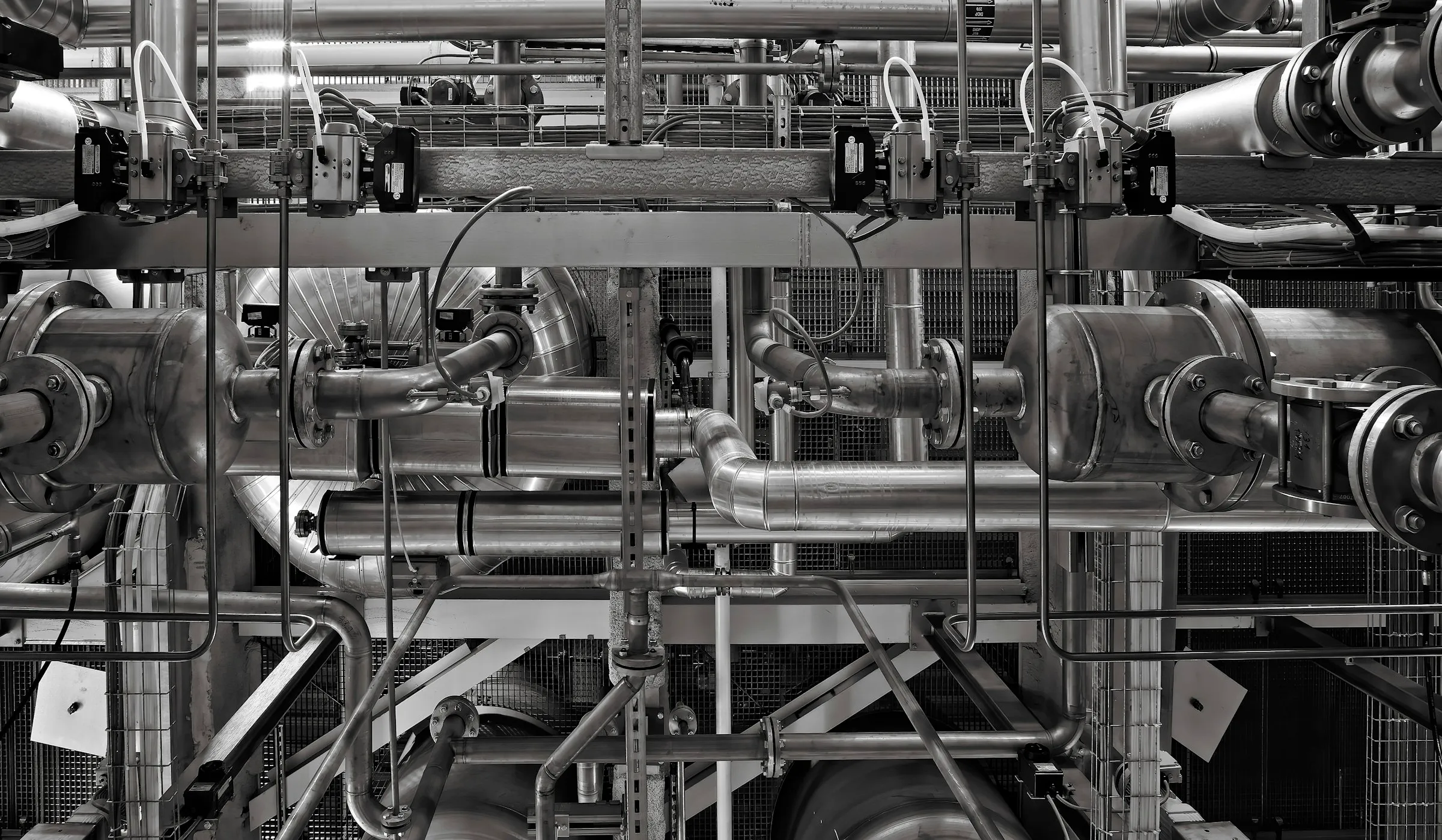 Industrial pipework and pressure vessels running across a plant gallery, with flanged joints, actuated valves and instrumentation